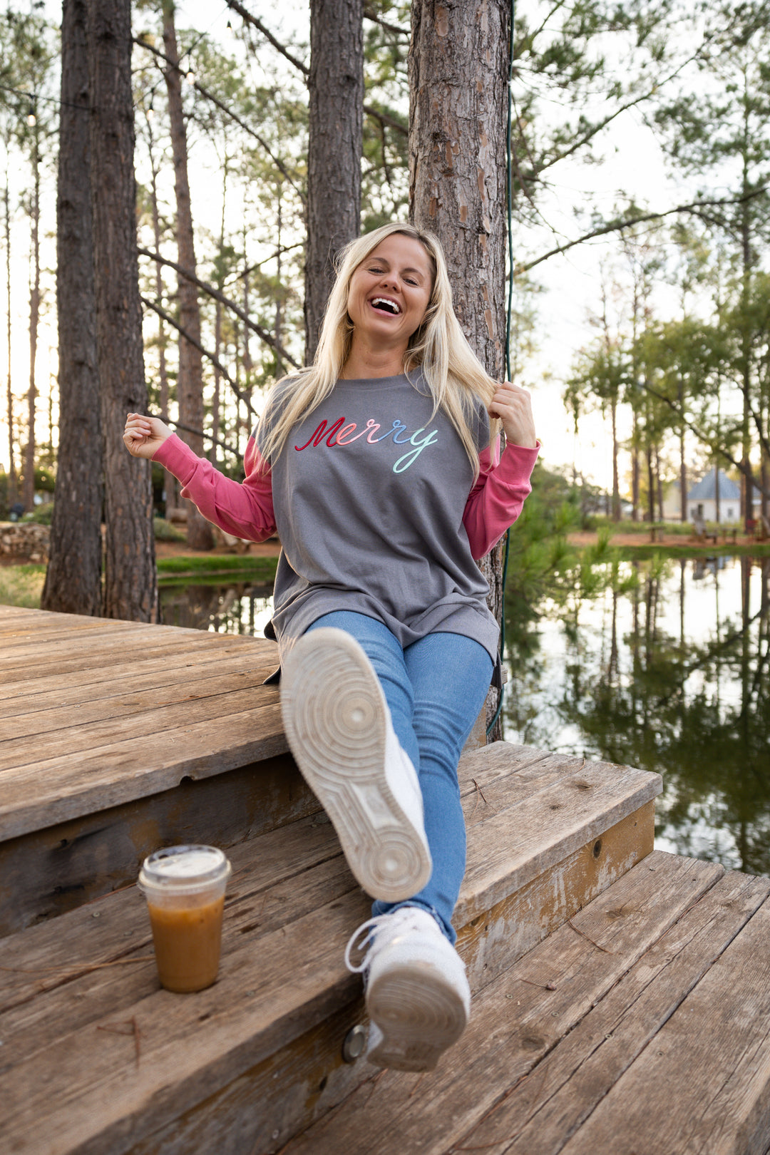 Casual grey and pink long-sleeve shirt with 'Merry' design, paired with blue jeans and sneakers outdoors.