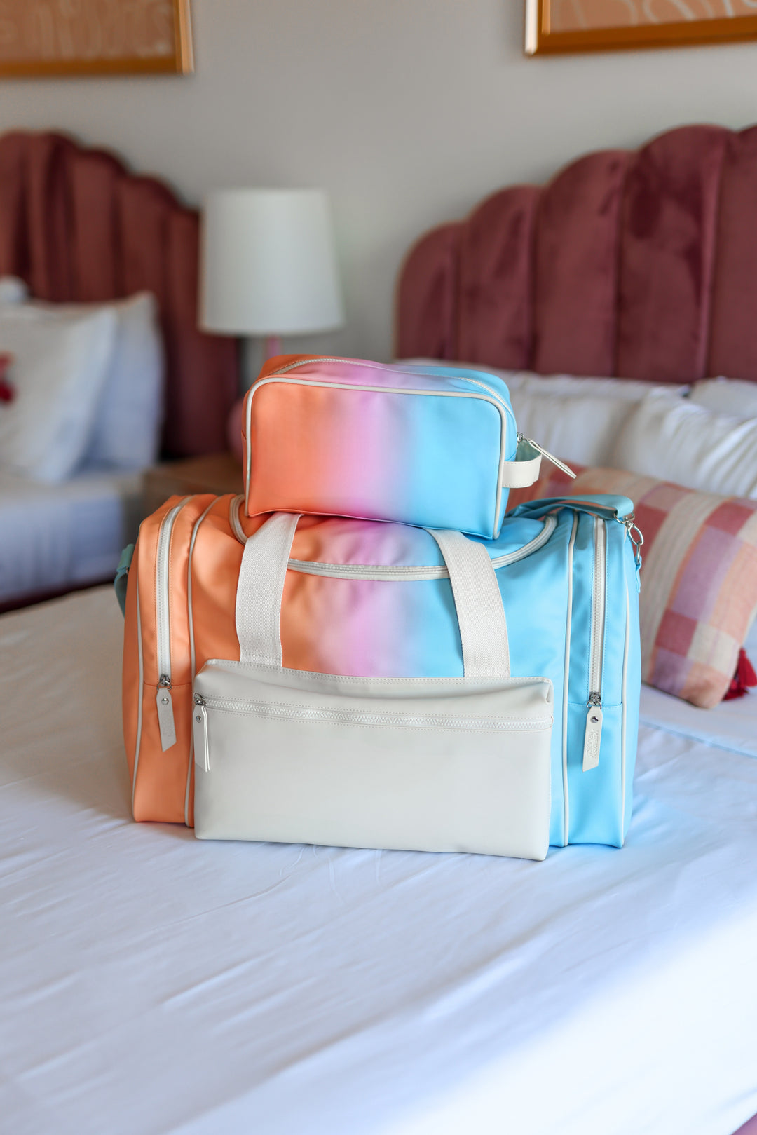 Colorful bags with 'NORAH' branding on a bed in a bedroom setting.