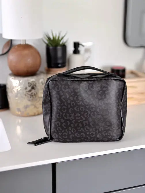 Stylish black leopard print cosmetic bag with handle, perfect for travel organization.
