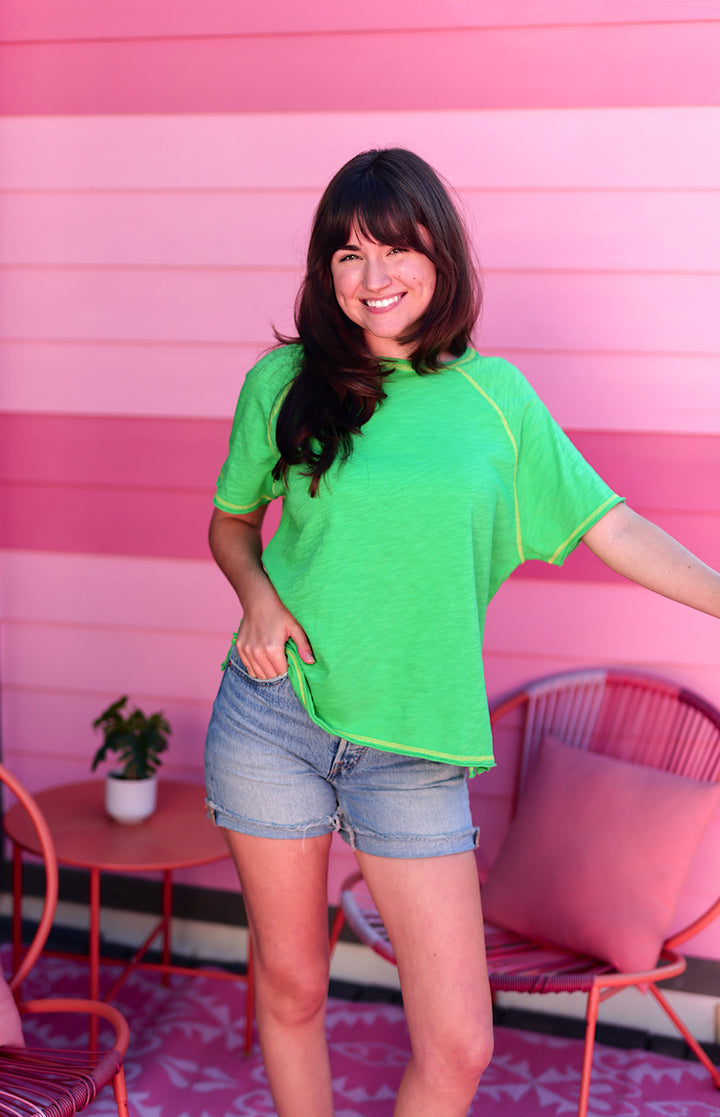 Bright green casual tee with yellow trim, paired with denim shorts, perfect for summer outings.