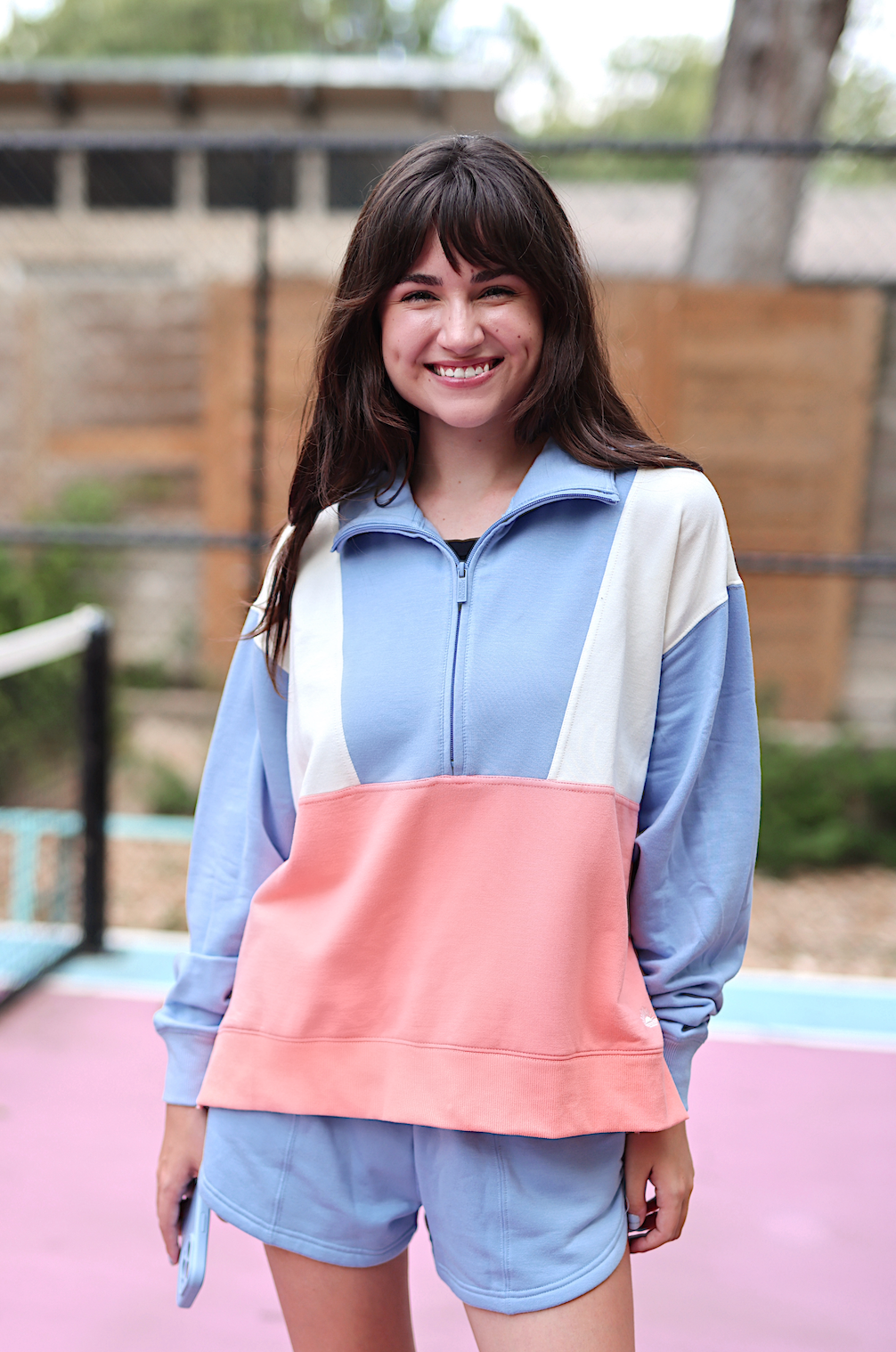 Stylish color-blocked women's athletic outfit in blue and peach, featuring a zip-up pullover and shorts.