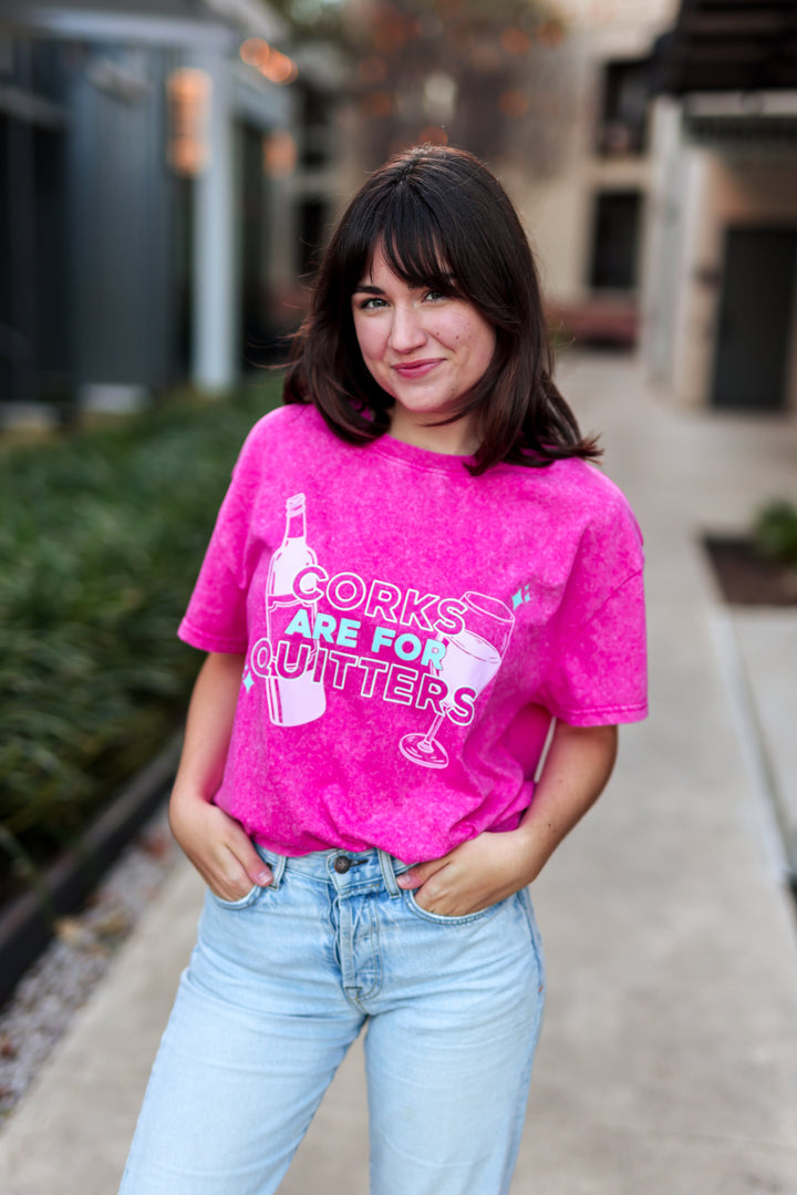 Person wearing a pink t-shirt with text and graphics, standing outdoors.