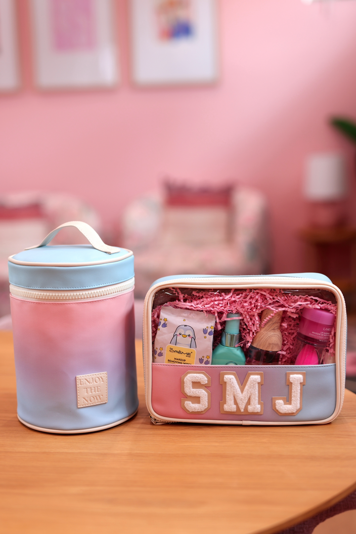 Pastel pink and blue cosmetic bag set with personalized initials and beauty products inside.
