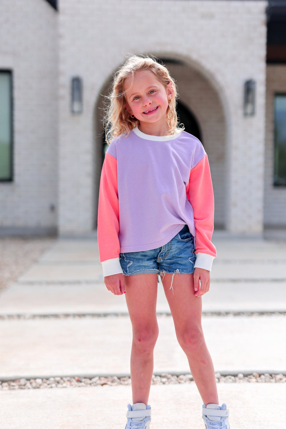 Youth sweatshirt in lavender and coral, featuring long sleeves and a relaxed fit, perfect for casual outings.