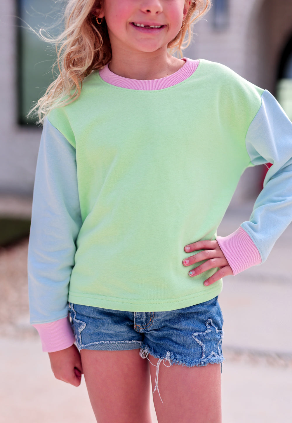 Kids' pastel green and blue long-sleeve sweatshirt with pink accents, perfect for casual spring outfits.