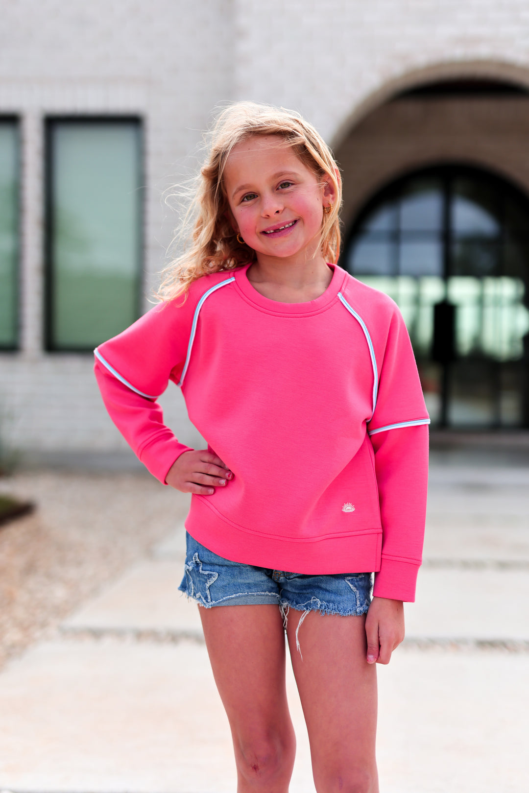 Cute pink kids' sweatshirt made of soft material, featuring raglan sleeves and stylish accent details.