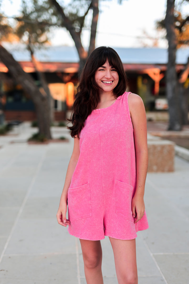 Woman wearing a pink romper standing outdoors with blurred background