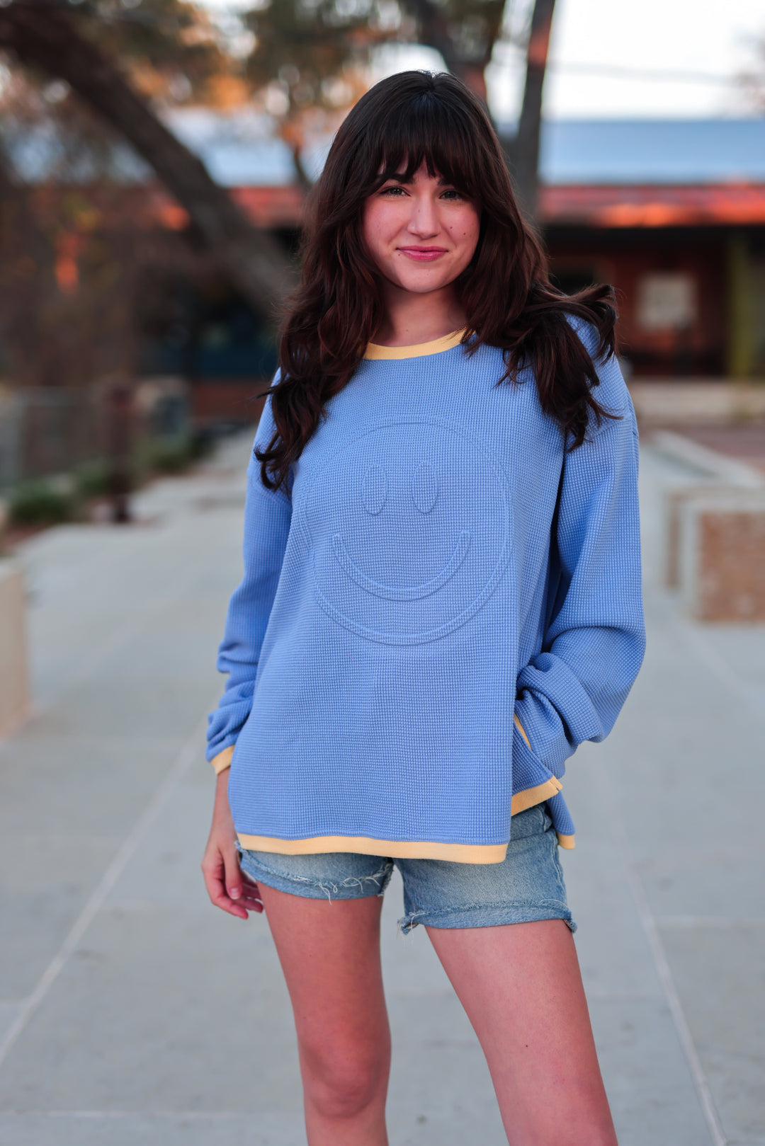 Light blue smiley face sweatshirt with yellow trim, perfect for casual style and comfort.