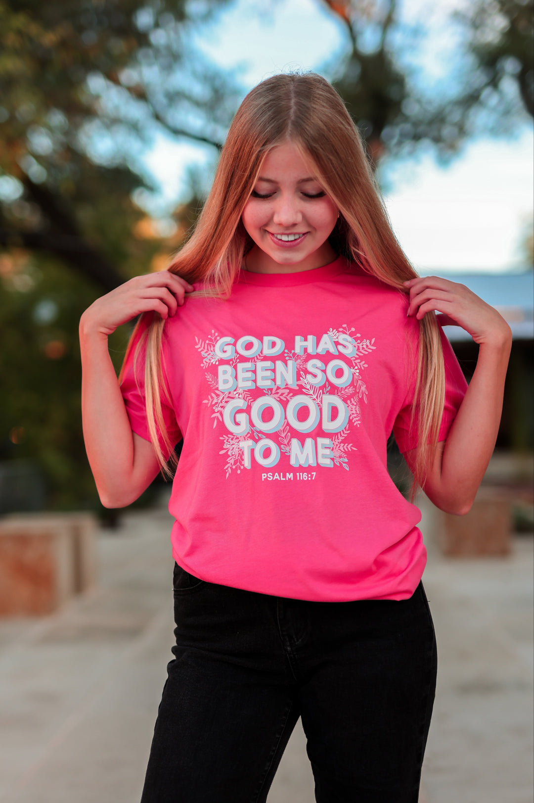 Person wearing a pink t-shirt with a motivational quote outdoors