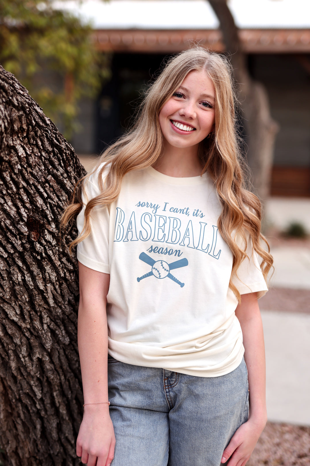 Woman wearing a 'Baseball Season' t-shirt standing next to a tree