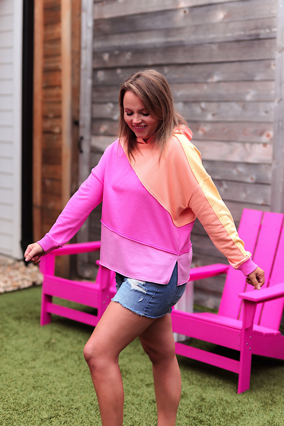 Colorful women's hoodie in pink and orange, featuring a relaxed fit and stylish design.