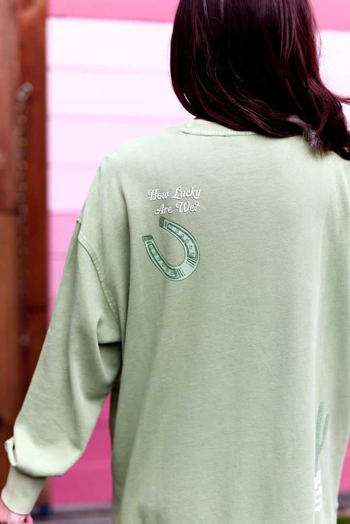 Green oversized sweatshirt featuring 'How Lucky Are We?' print and horseshoe design on the back.