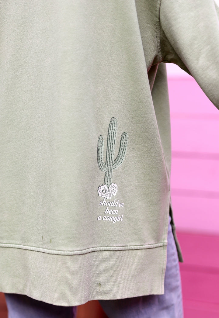 Light green sweatshirt with cactus design and 'should've been a cougirl' text, made from soft cotton.