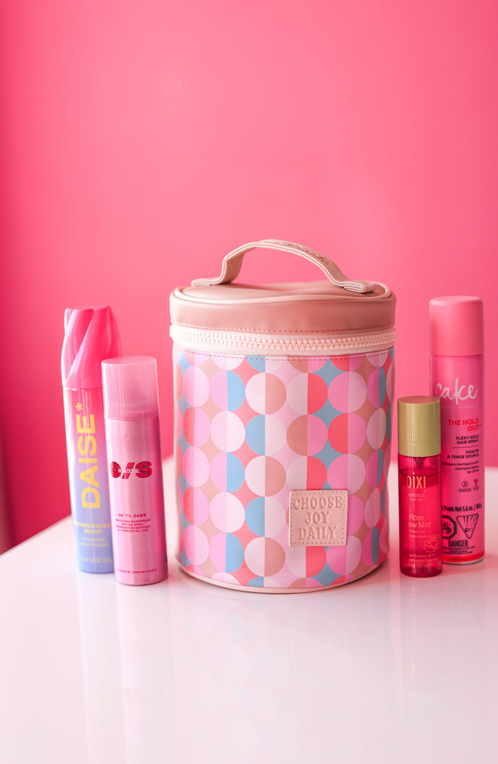 Colorful beauty bag with pink polka dots, containing hair products and a rose glow mist.