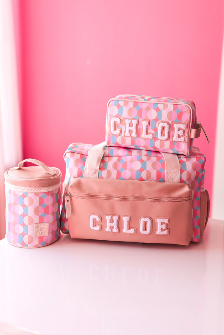 Colorful Chloe travel bag set in pink and blue, includes duffel, cosmetic pouch, and storage container.