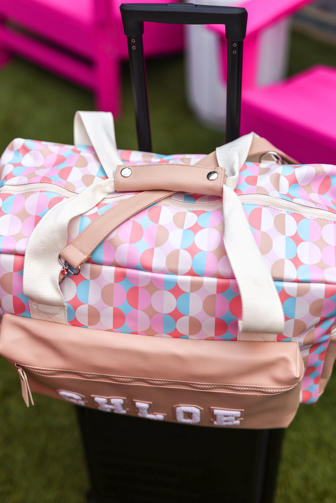 Colorful duffel bag with geometric pattern, beige accents, and a name tag, perfect for travel.