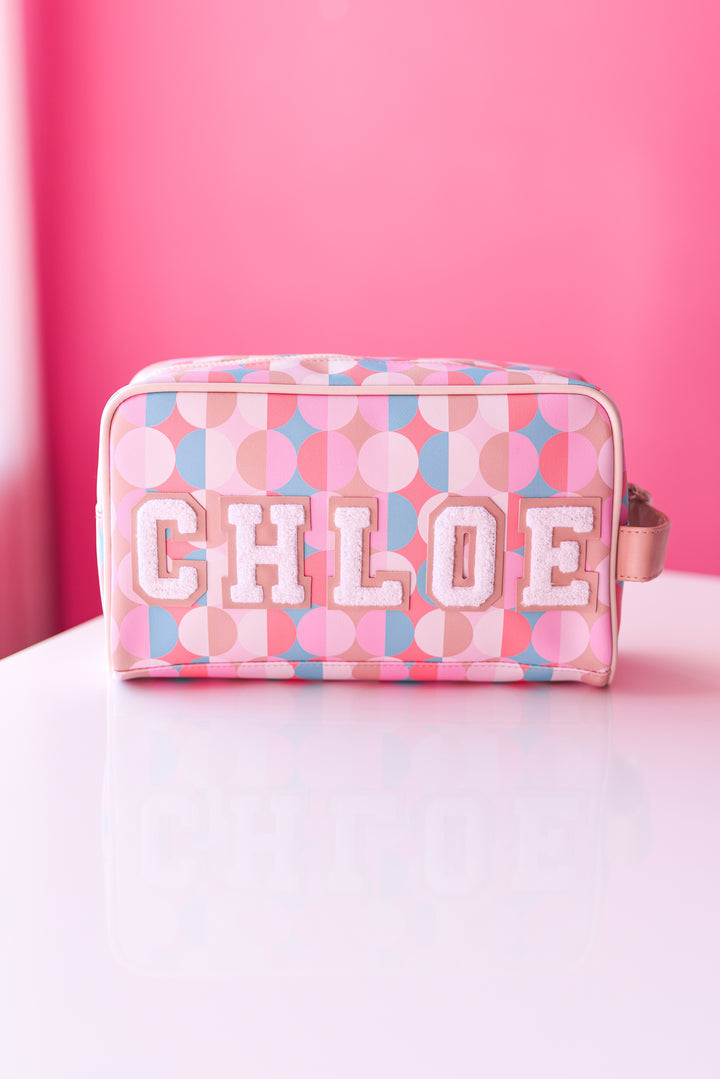 Chloe cosmetic bag in pastel pink and blue with circular patterns and textured letters.