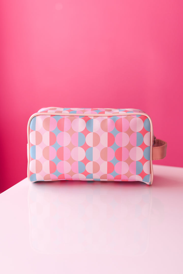 Colorful geometric print cosmetic bag in pink and blue, made of durable material with a convenient handle.