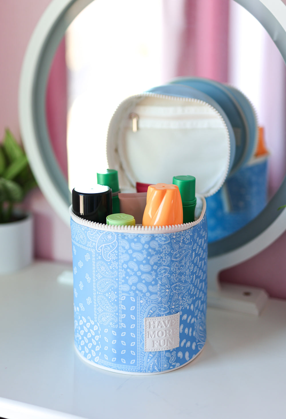 Blue cylindrical bag with full-size products on a white surface with pink background
