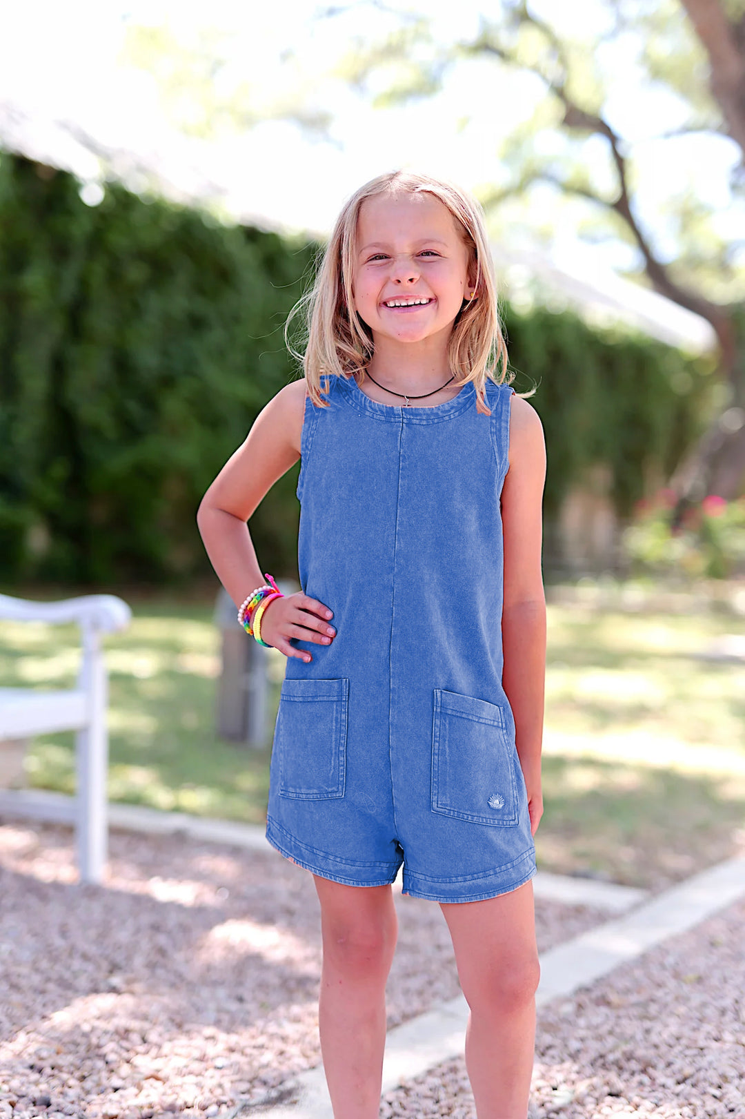 Young girl in a blue romper outside.