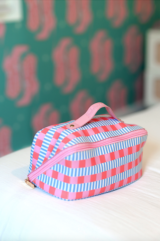 Colorful striped cosmetic bag in pink and blue, featuring zip closure and handle, perfect for travel.