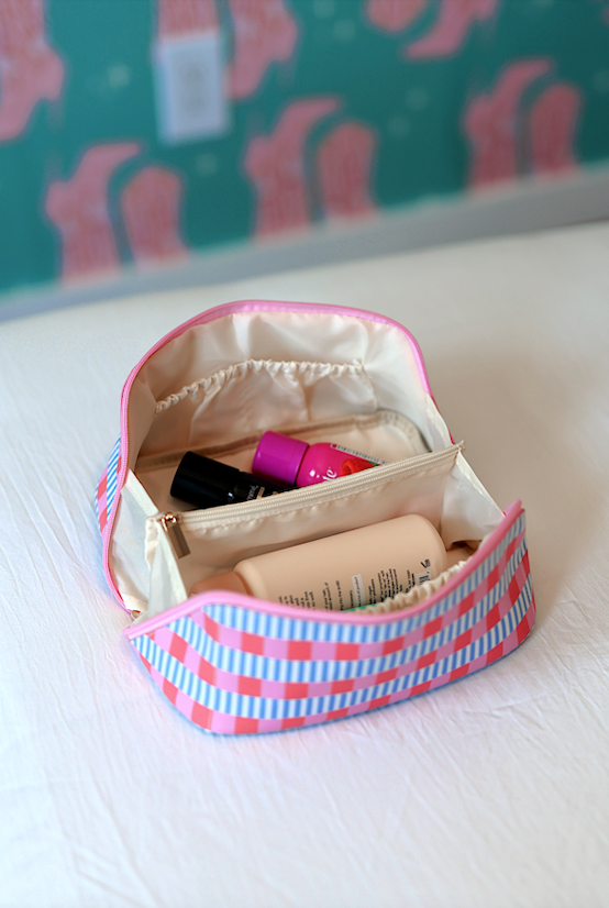 Colorful striped makeup bag in pink and blue, featuring zippered compartments for organizing cosmetics.