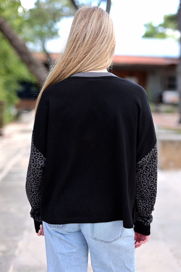 Back view of black sweatshirt with leopard print sleeves, casual style, perfect for everyday wear.