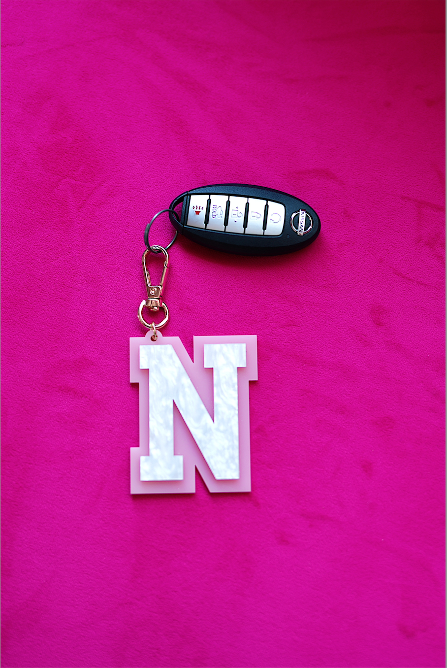 Stylish pink keychain with a white 'N' letter design, perfect for personalizing keys or bags.