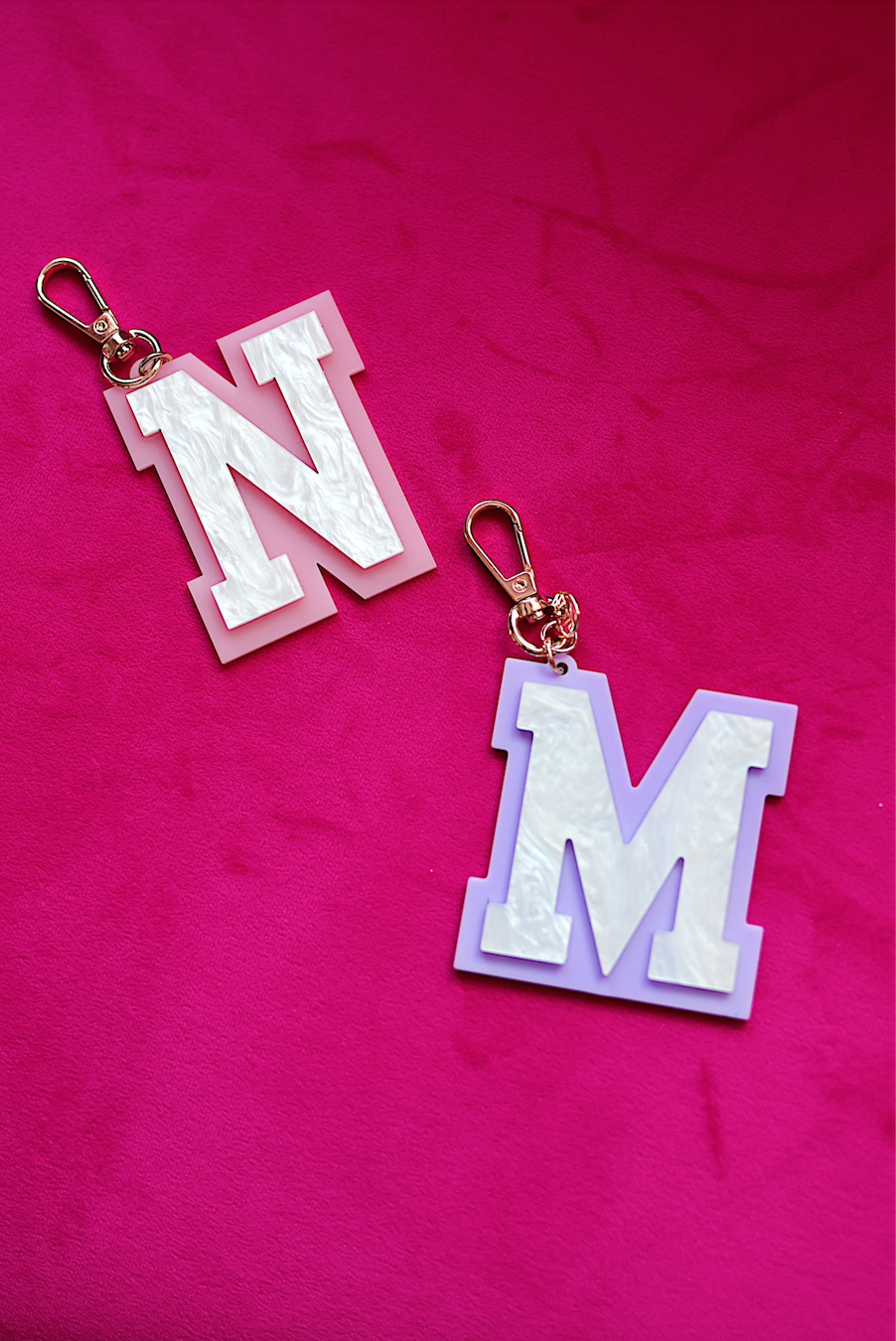 Colorful acrylic keychains featuring letters N and M, with rose gold clasps and a stylish design.