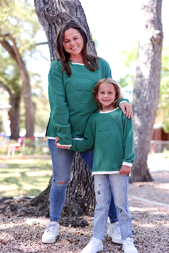 Matching green waffle knit sweatshirts for mom and daughter with smiley face design, casual and cozy style.