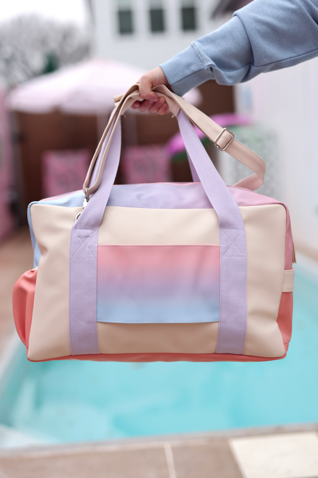 Colorful gradient weekend duffel bag in pastel shades of blue, pink, and beige, made from durable material.