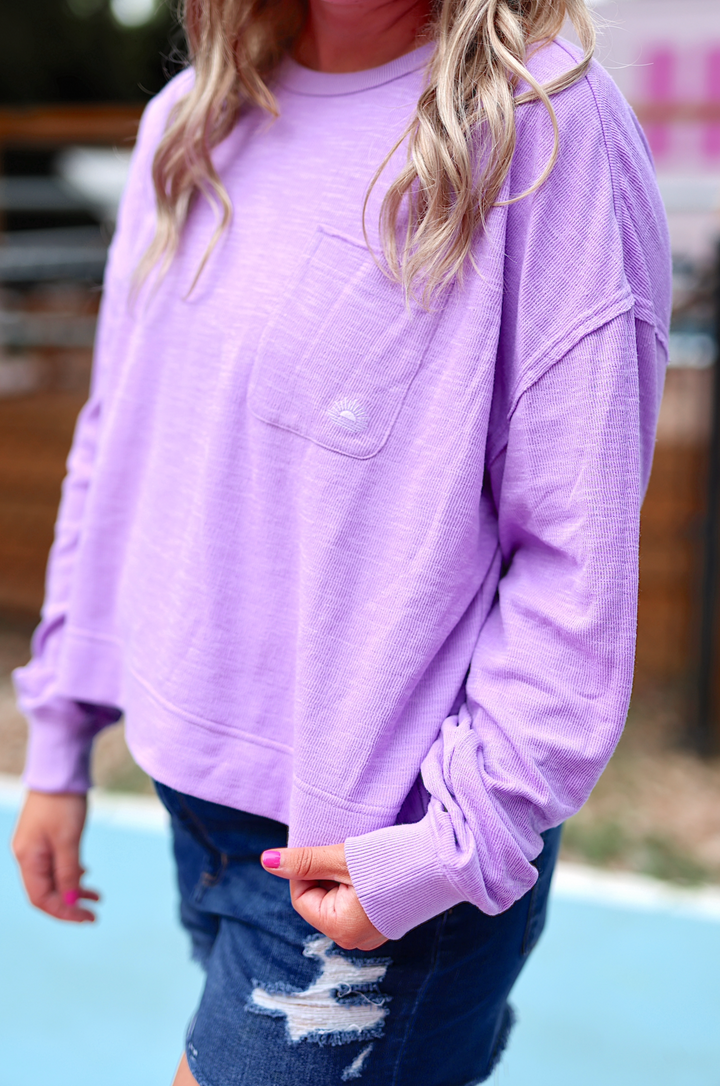 Light purple oversized long-sleeve sweatshirt with pocket detail, casual style for women.