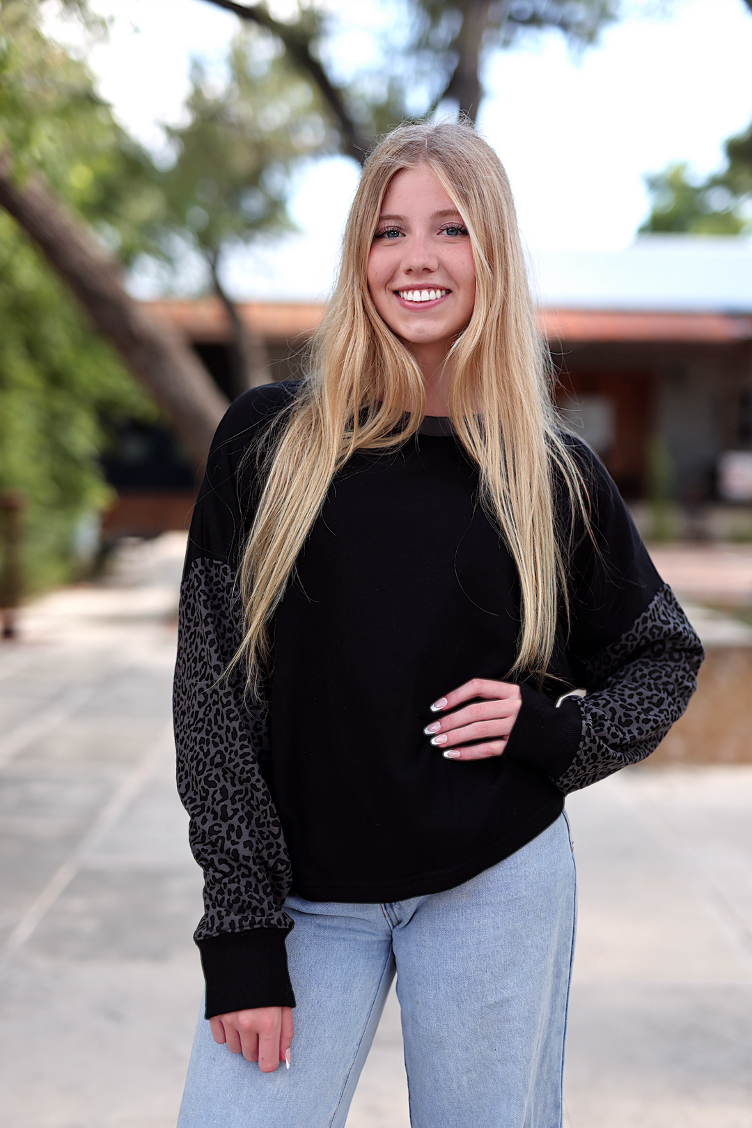Black sweatshirt with leopard print sleeves, casual style, soft material, perfect for everyday wear.