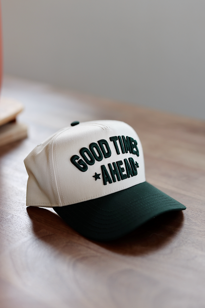 Beige baseball cap with green 'GOOD TIMES AHEAD' embroidery, perfect for casual outings.
