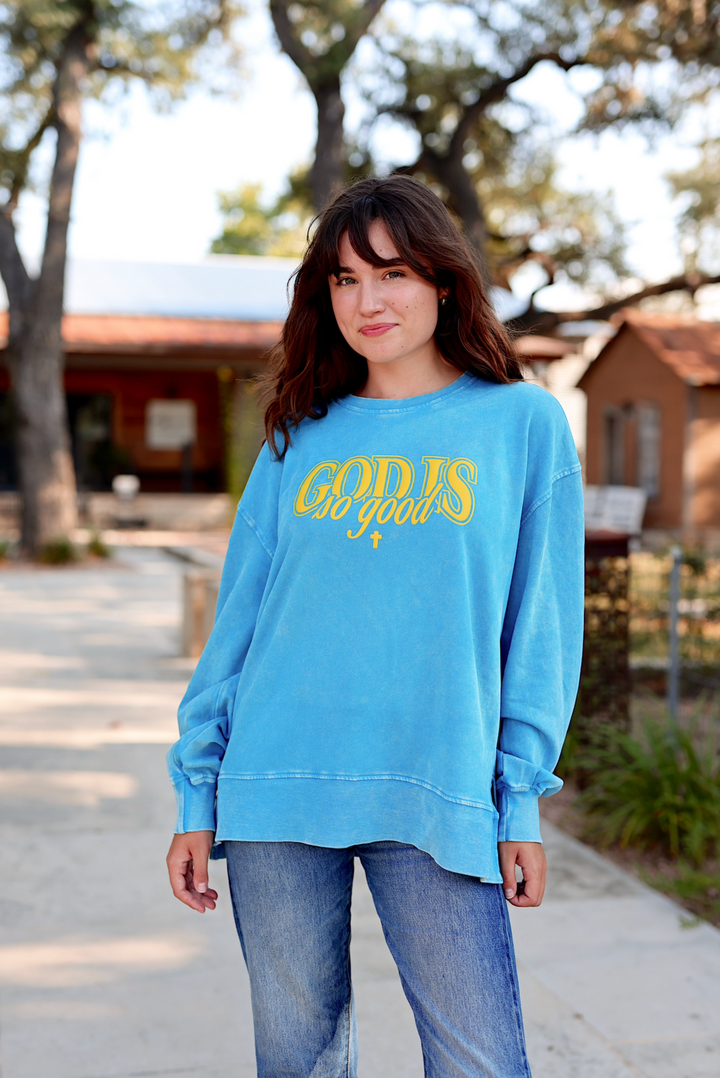 Light blue oversized sweatshirt with 'GOD IS so good' graphic, perfect for casual wear.