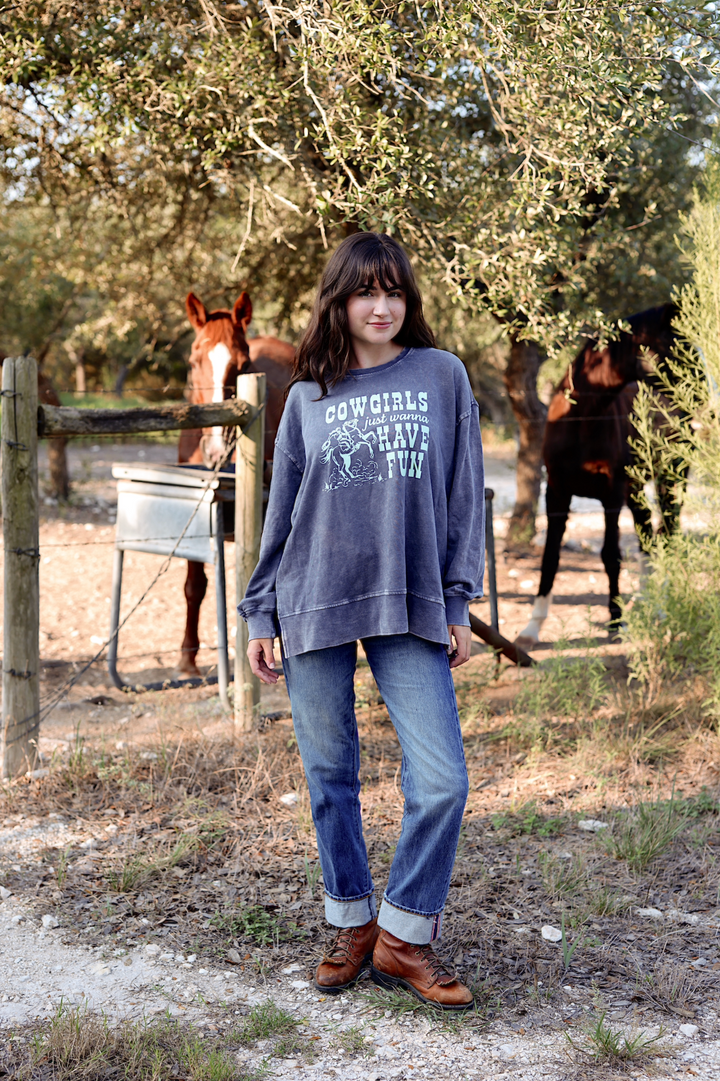 Cozy gray cowgirl sweatshirt with fun graphic, paired with blue jeans and brown boots in a rustic outdoor setting.