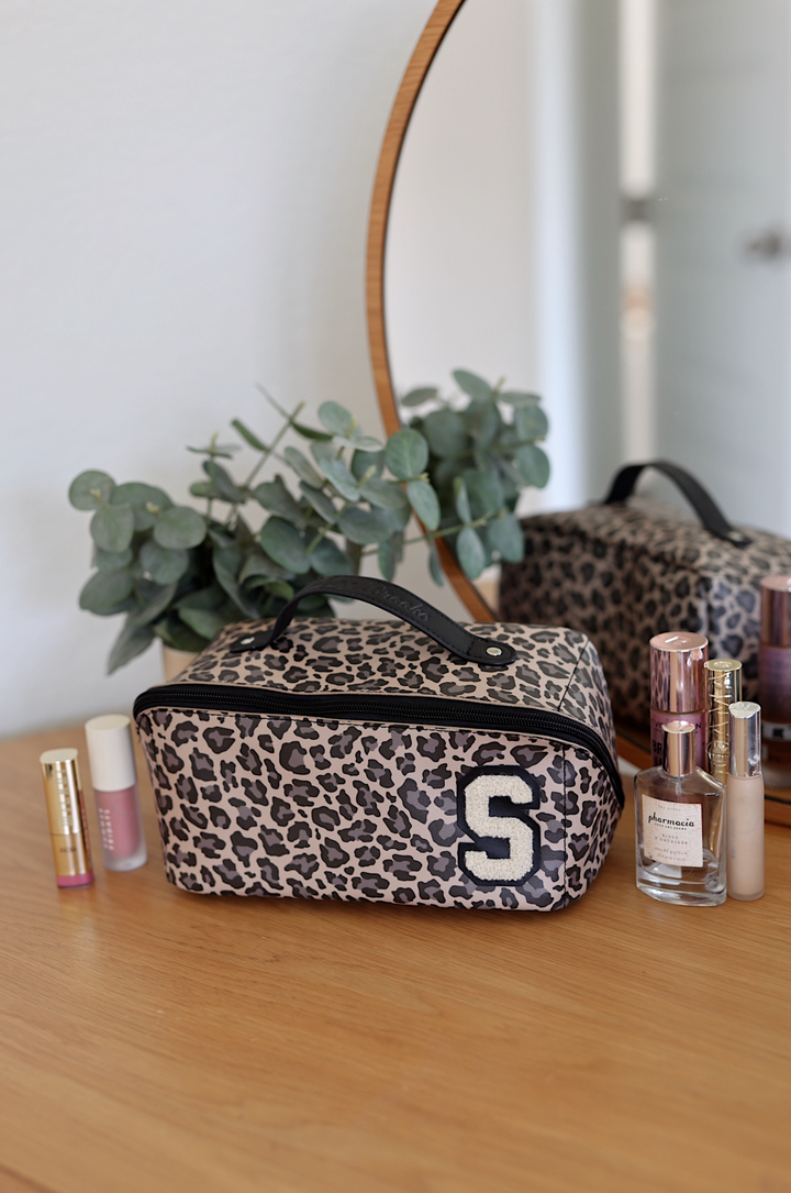 Stylish leopard print makeup bag with handle and initial S, perfect for cosmetics storage.