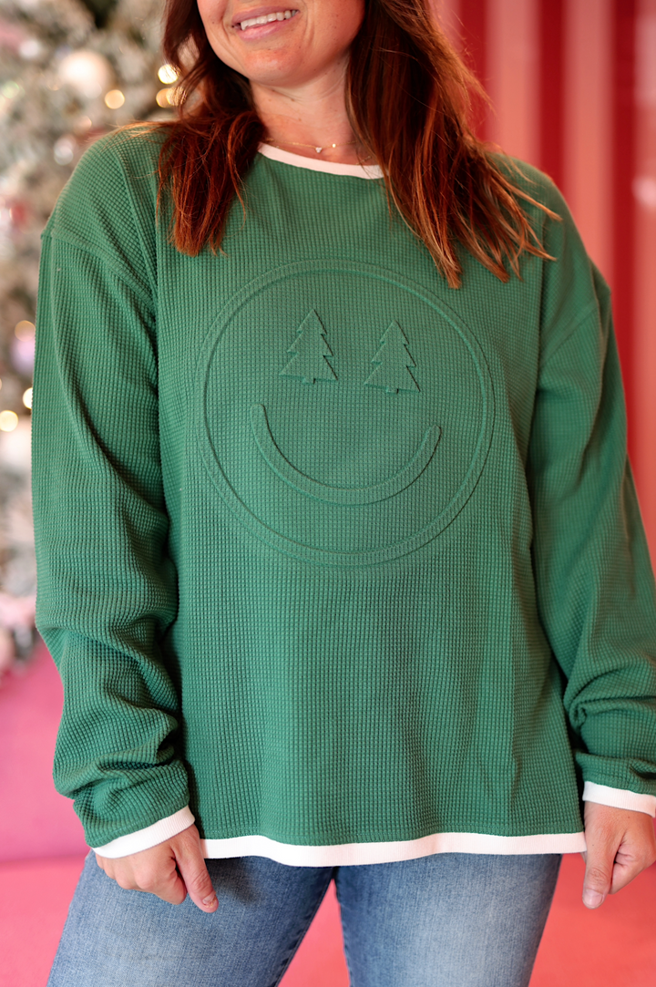 Green waffle-knit sweater with smiley face design and white trim, perfect for cozy casual wear.