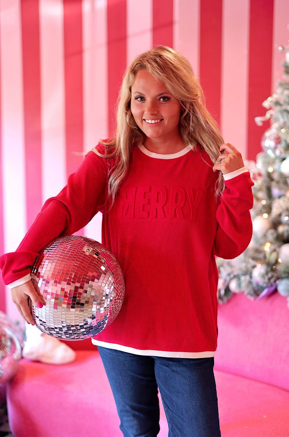Red 'MERRY' sweat top in ribbed fabric, perfect for festive celebrations, styled with blue jeans.