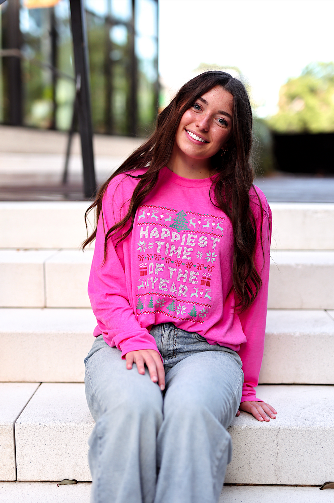Bright pink long-sleeve Christmas graphic tee with 'Happiest Time of the Year' print