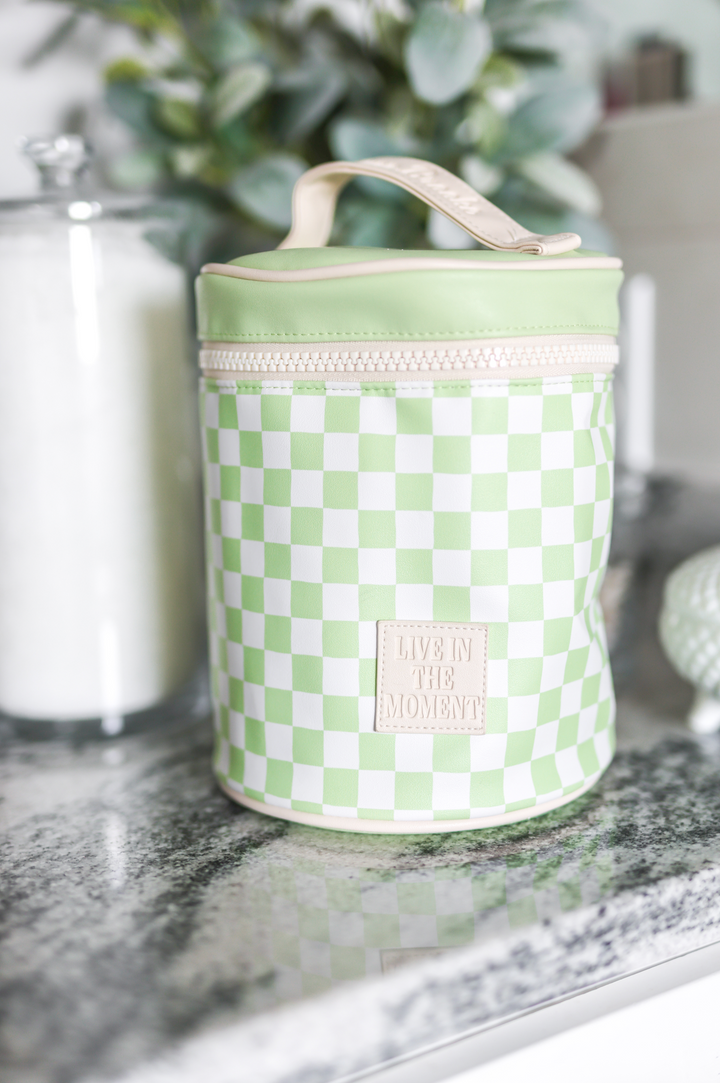 Green and white checkered cooler bag on a marble surface with decorative items in the background