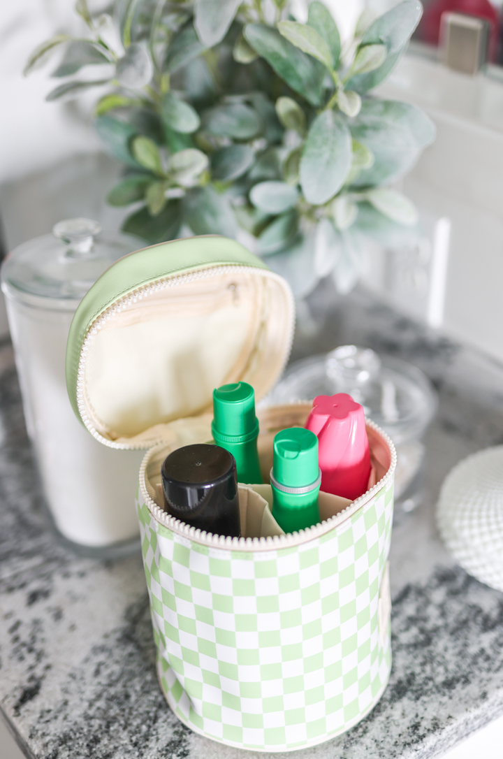 Green checkered case with makeup items on a marble surface