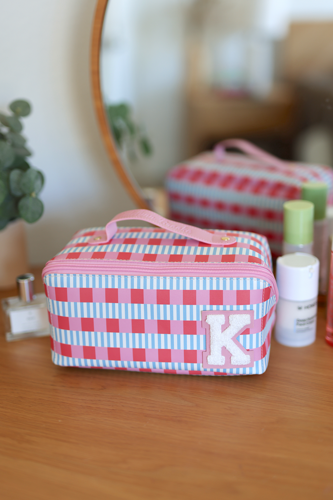 Stylish pink striped cosmetic bag with handle and initial ‘K’, perfect for travel and organization.