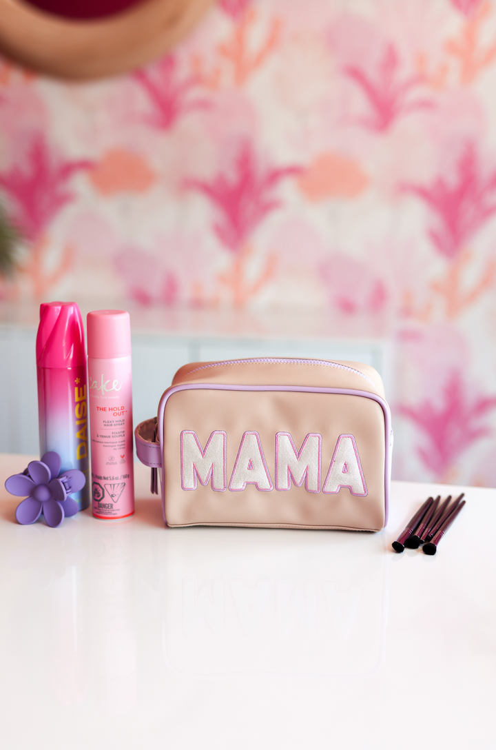 MAMA cosmetic bag in pink and beige faux leather with beauty products and brushes on a white table.