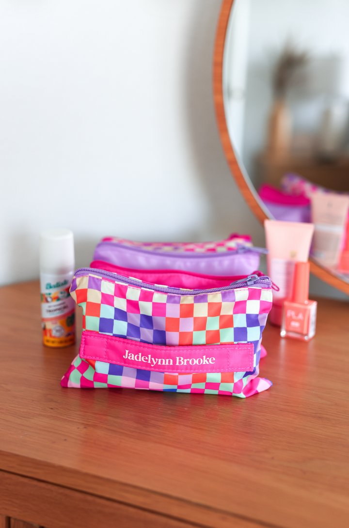 Colorful checkered cosmetic bag by Jadelynn Brooke, featuring pink, purple, and pastel colors.