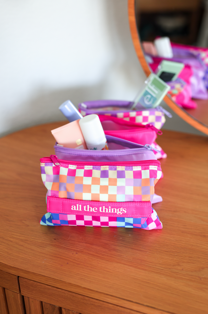Colorful checkered cosmetic pouch in pink, purple, and orange, featuring the phrase 'all the things'.