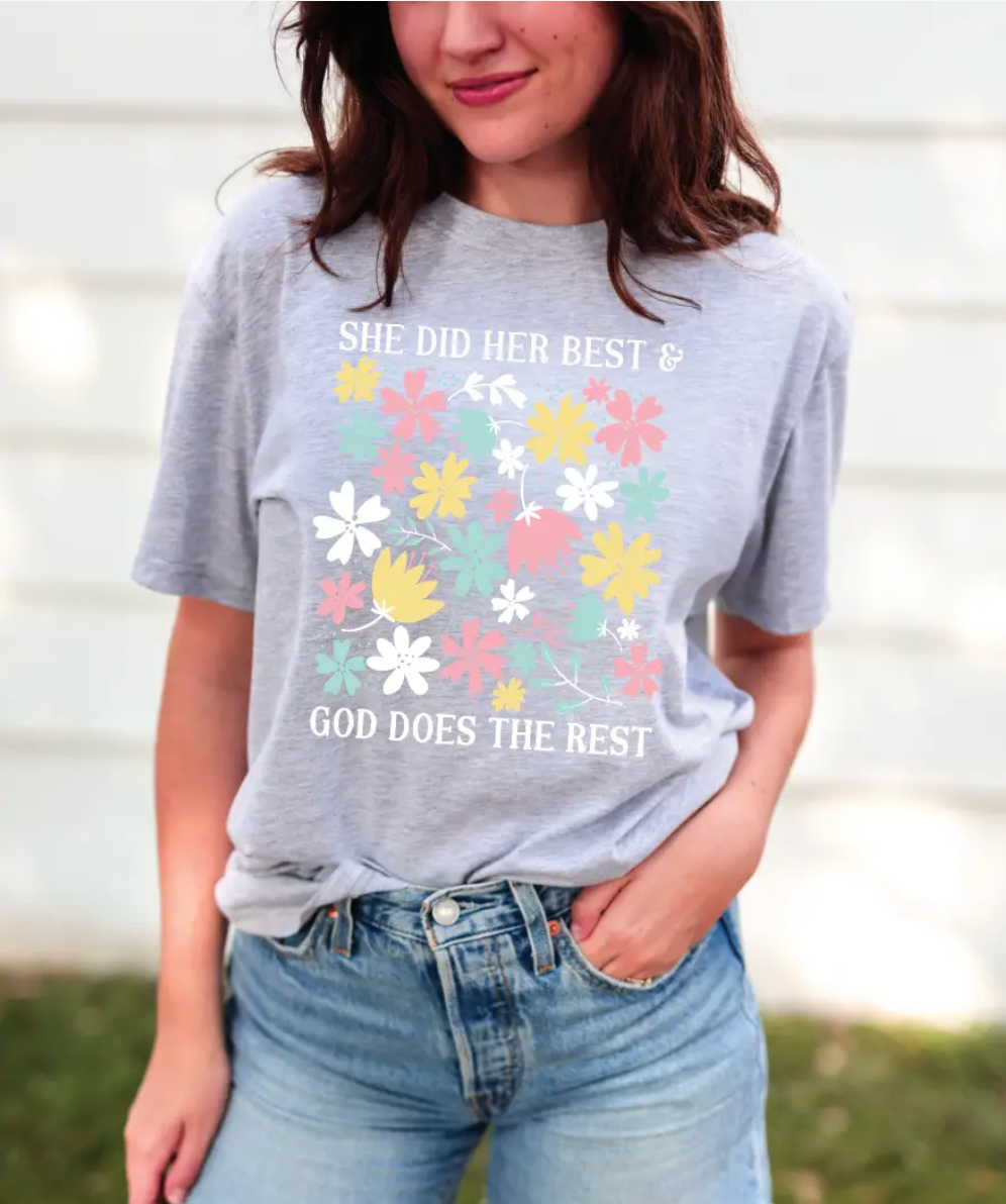 Person wearing a gray t-shirt with floral design and text outdoors