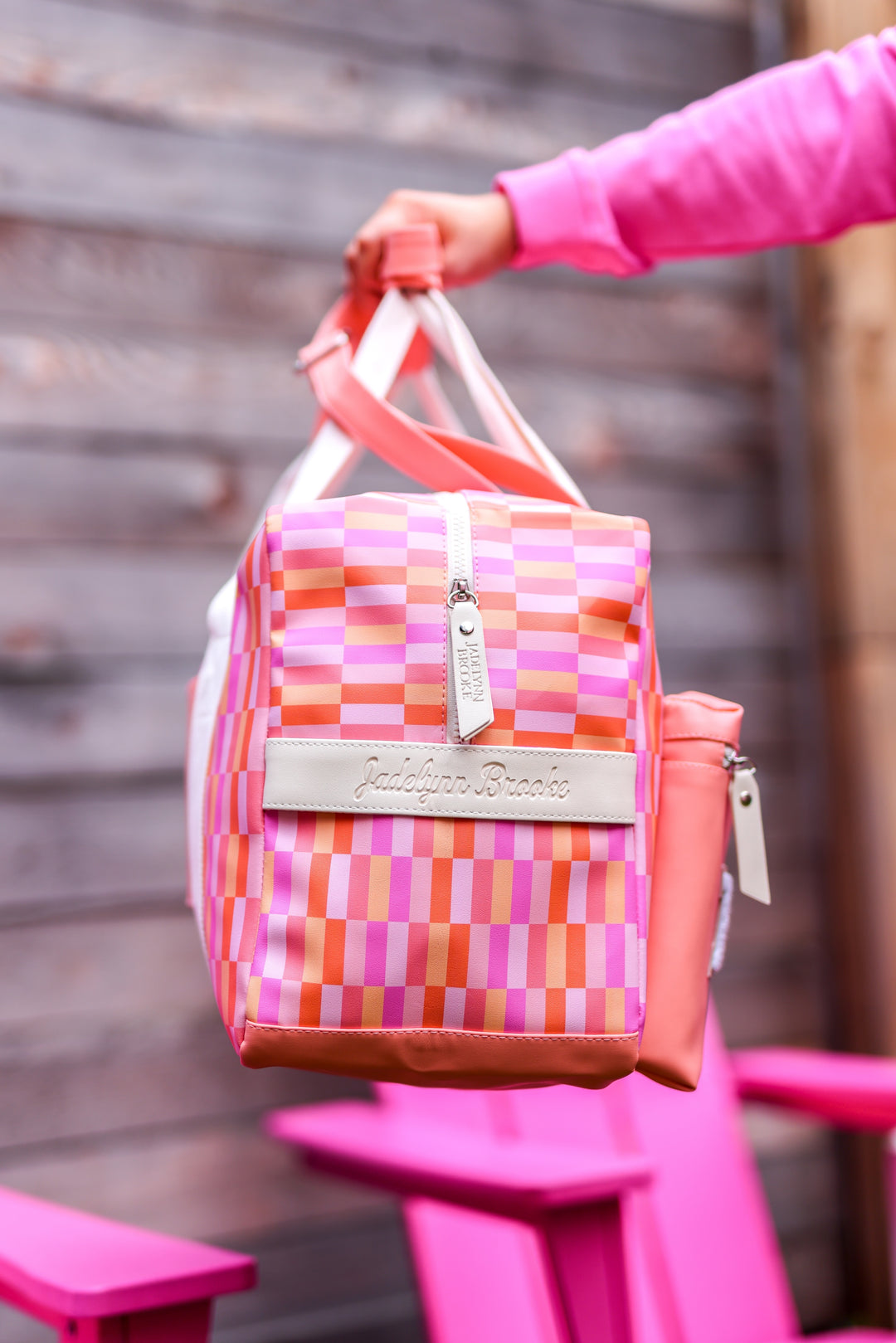 Colorful insulated tote bag in pink and orange plaid pattern, featuring a sturdy zipper and stylish branding.