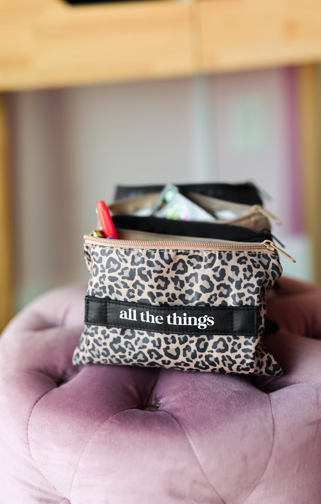 Leopard print pouch with 'all the things' text on a pink cushion