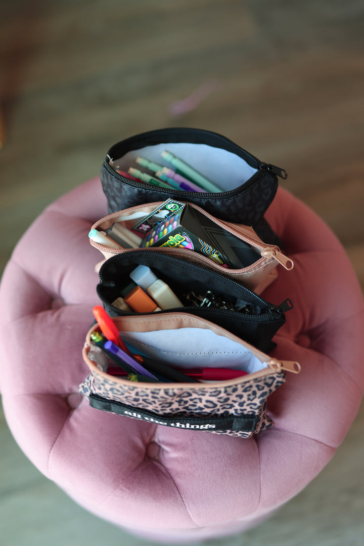 Small pouches with stationery items on a pink cushion